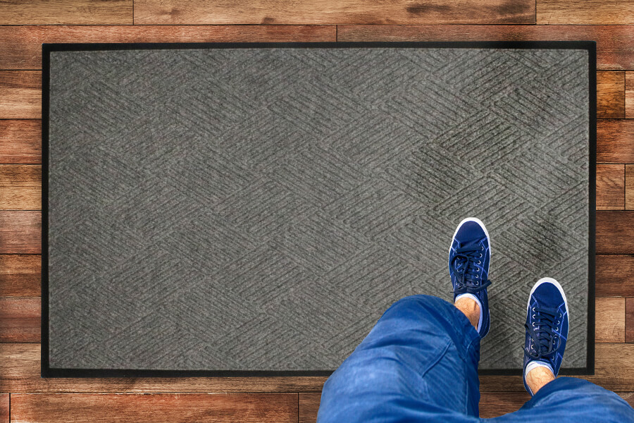 a person standing on a waterhog mat with diamond pattern