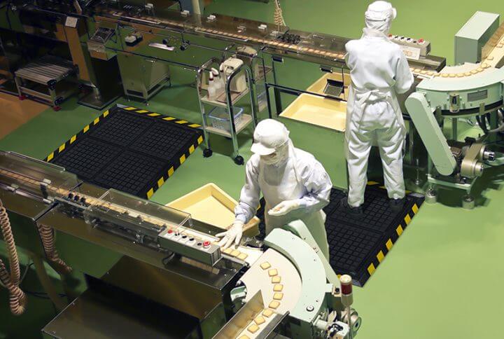factory workers at work standing on anti-fatigue mats